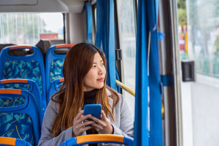 Asian Woman sitting  in the bus and using mobile phone when traveling around Dukezong ancient Old Town, Lijiang City, in Yunnan, China. holiday and travel concept,の写真素材