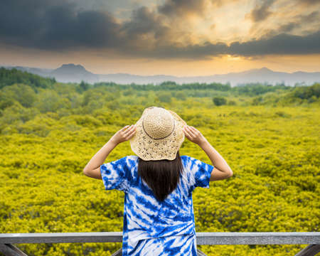 Asian traveler woman holding the hat and standing on wooden bridge for travel at Tung Prong Thong...