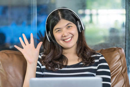 Asian business woman waving hand for say hello when making video call to friend with social...