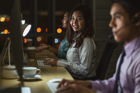 Portrait of Asian Female customer care service with business man smiling and working hard late in...