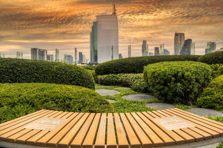 pandemic, new normal Concept, PLEASE KEEP YOUR DISTANCE Text on the waiting chair in out door and garden with cityscape backgroundの写真素材