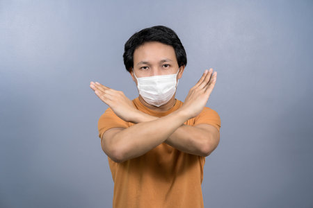Portrait of asian male wearing face surgical mask and say no action to coronavirus  infection on blue color background, covid19 outbreak and pandemic, healthcare and protection against virus conceptの写真素材