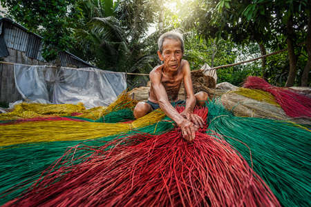 Vietnamese Old man craftsman making the traditional vietnam mats in the old traditional village at dinh yen, dong thap, vietnam, tradition artist conceptの写真素材