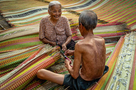 Top view of old Vietnamese lover craftsman making the traditional vietnam mats with happiness action in the old traditional village at dinh yen, dong thap, vietnam, tradition artist conceptの写真素材