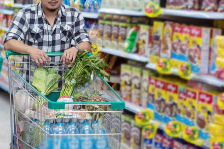 Closeup Young Asian men Hand holding the trolley for shopping over the store blurred in department store bokeh backgroundの写真素材