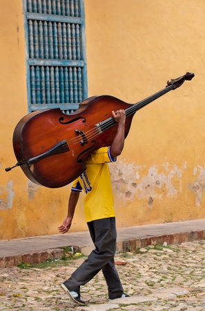 man carring a bass on a street of Trinidad, Cubaの写真素材