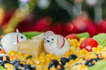 Boiled eggs mice with radish ears and piece of cheese between them, sitting on cornの写真素材