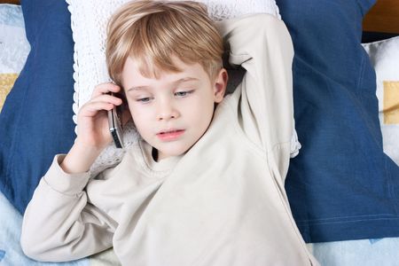 Little boy talking by mobile phone very emotionalの写真素材