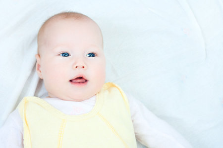 the portrait of baby girl lying down on white and smiling