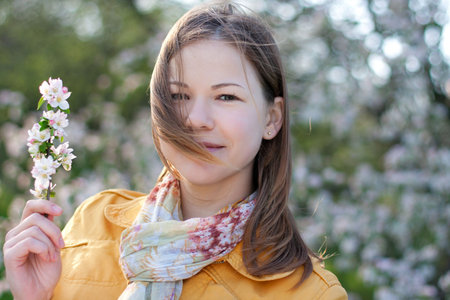 young woman posing with a blooming branch in a spring park