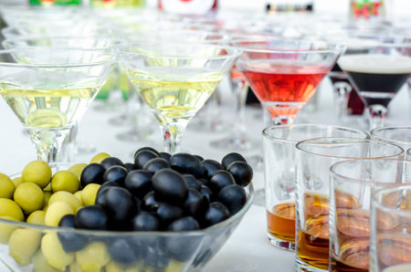 Glasses of martini with olives and glasses with cognac. Alcoholic beverages served at bar. Club atmosphere.の写真素材
