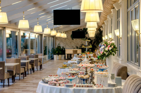 Delicious wedding reception candy bar dessert table full with cakes and sweets and a flower vase with hydrangeas on the backgroundの写真素材