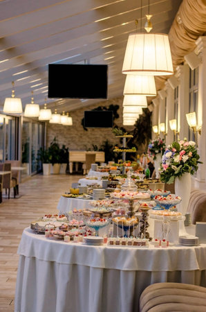 Delicious wedding reception candy bar dessert table full with cakes and sweets and a flower vase with hydrangeas on the backgroundの写真素材
