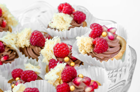 Candy Bar. Delicious sweet buffet with chocolate tartlets and raspberry and grapefruit cupcakes on glass plate. Happy luxury birthday and wedding concept. Party sweets.の写真素材