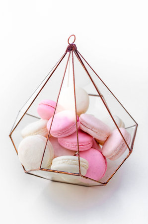 Macarons in a metallic glass vase on a table on the background of a magnificent wedding room. Sweet macarons.の写真素材