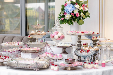 Delicious wedding reception candy bar dessert table full with cakes and sweets and a flower vase with hydrangeas.の写真素材
