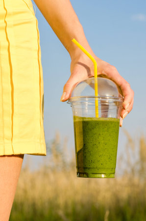 Diet. Healthy eating .Woman hand holding smoothies on the background blurred nature. Fresh green detox vegetable juice. Healthy lifestyle, vegetarian food.  Nutrition Concept.の写真素材
