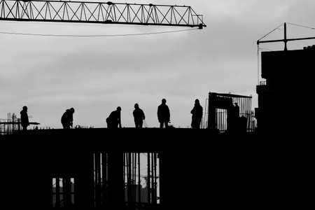 Construction workers outdoors back lit by the setting sun.