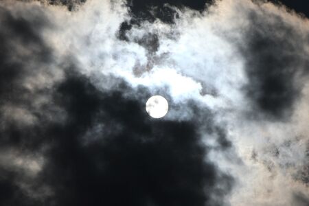 The sky is overcast, but the bright moon is still visible.の写真素材