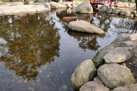 Smooth water in a small pond with stone boulders.の写真素材