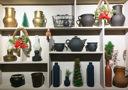 Christmas home decor as part of the interior, home utensils clay pots, old lamps, Christmas wreath, artificial Christmas tree on the shelves eve the new yearの写真素材
