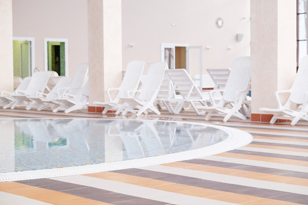 Swimming pool and many white empty chaise-longueのeditorial素材