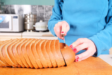 Closeup female hands cutting bread on wooden board