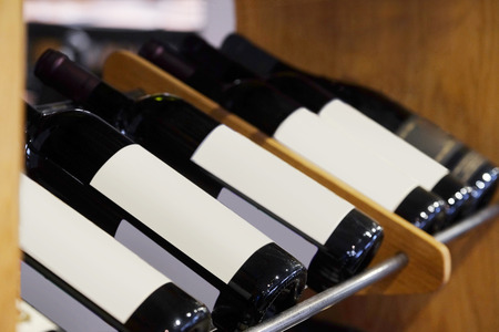 Bottles of red wine on a wooden shelf in the restaurantの写真素材