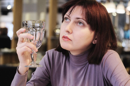 Woman holding an empty glass in the restaurantの写真素材