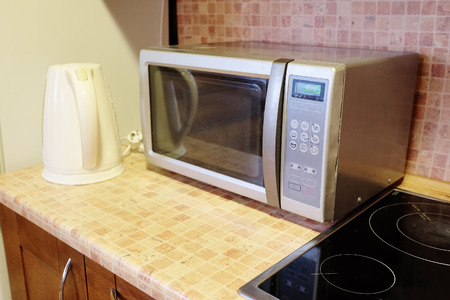 Electric kettle and microwave oven in the kitchen environmentの写真素材