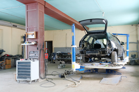 Black crashed car on stocks in a car repair stationのeditorial素材