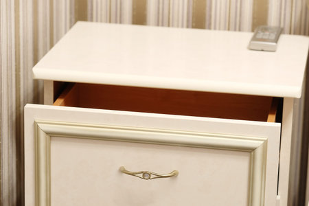 commode with an open drawer and a clicker on it in a hotel room