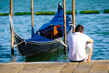 Venice, Italy - July, 28, 2017: man sits near the gondola in Venice, Italyのeditorial素材