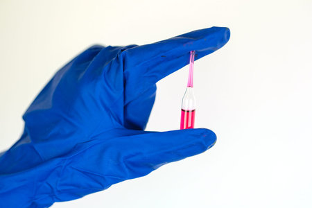 hand in a blue gloves brings an ampoule