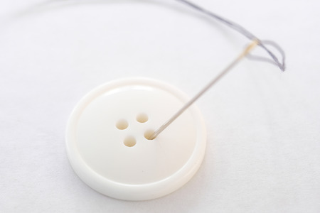 image of a thread, needle and buttonの写真素材