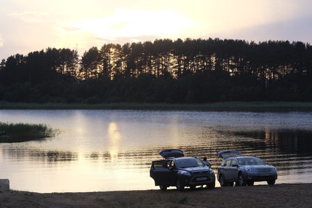 Two cars on the shore of a lake in the evening