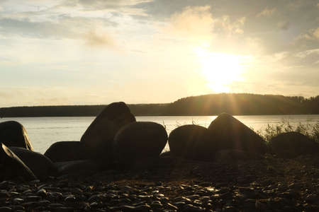 Sunset over the lake. Stones on the shore of the lake.の写真素材