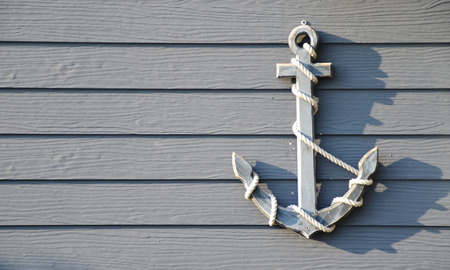 Grey anchor hanging on the wooden wallの写真素材