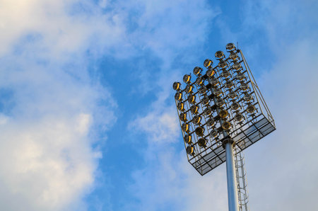 Football stadium spotlight pole on blue sky background