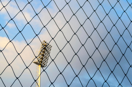 Black soccer net texture against  blue sky and spotlight pole  background