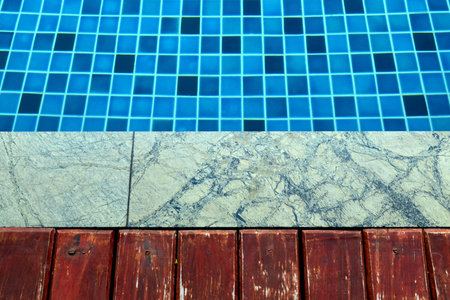 Wooden and marble floor beside blue swimming pool