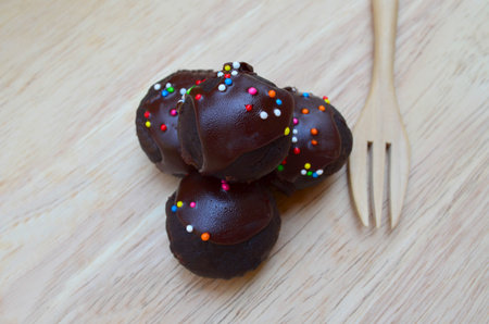 Delicious and soft fresh homemade chocolate ball cake topping with candy sprinkle on wooden board