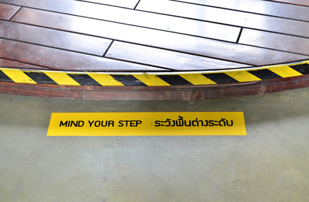 Yellow and black warning sign on step stating "Mind Your Step" - safety sign conceptの写真素材
