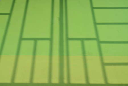 Square geometric shadow texture on yellow and green cement wallの写真素材