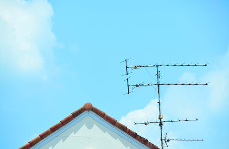Television antenna against fluffy blue sky