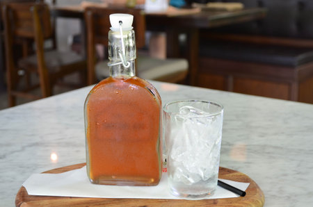 Rose iced tea in glass bottle with a glass of ice on wooden boardの写真素材
