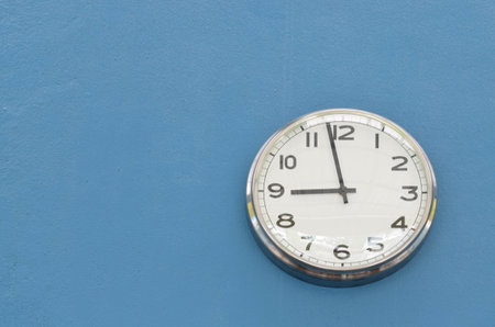 White round wall clock hanging on blue concrete wall
