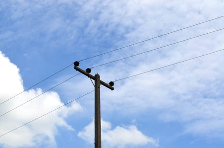 Electrical pole against hazy blue sky with power lines