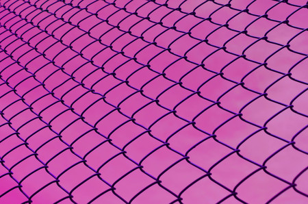 Security wire mesh fence over pink backgroundの写真素材
