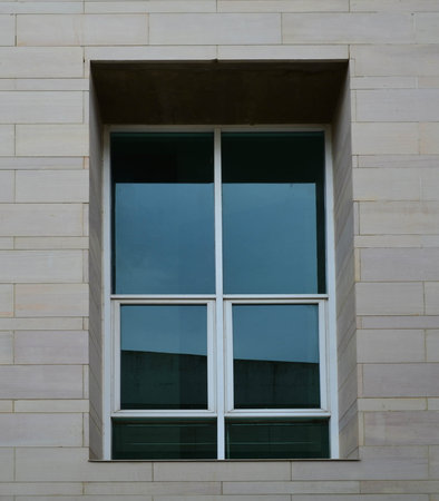 Glass window with white aluminium frame on sand stone wall